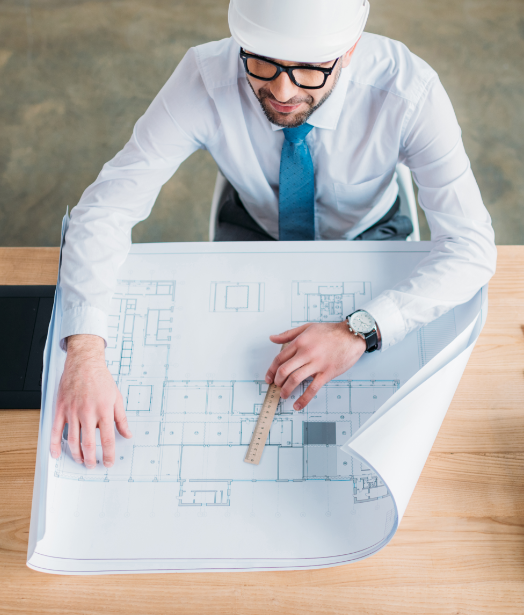 um homem analisa o desenho de uma planta de uma construção